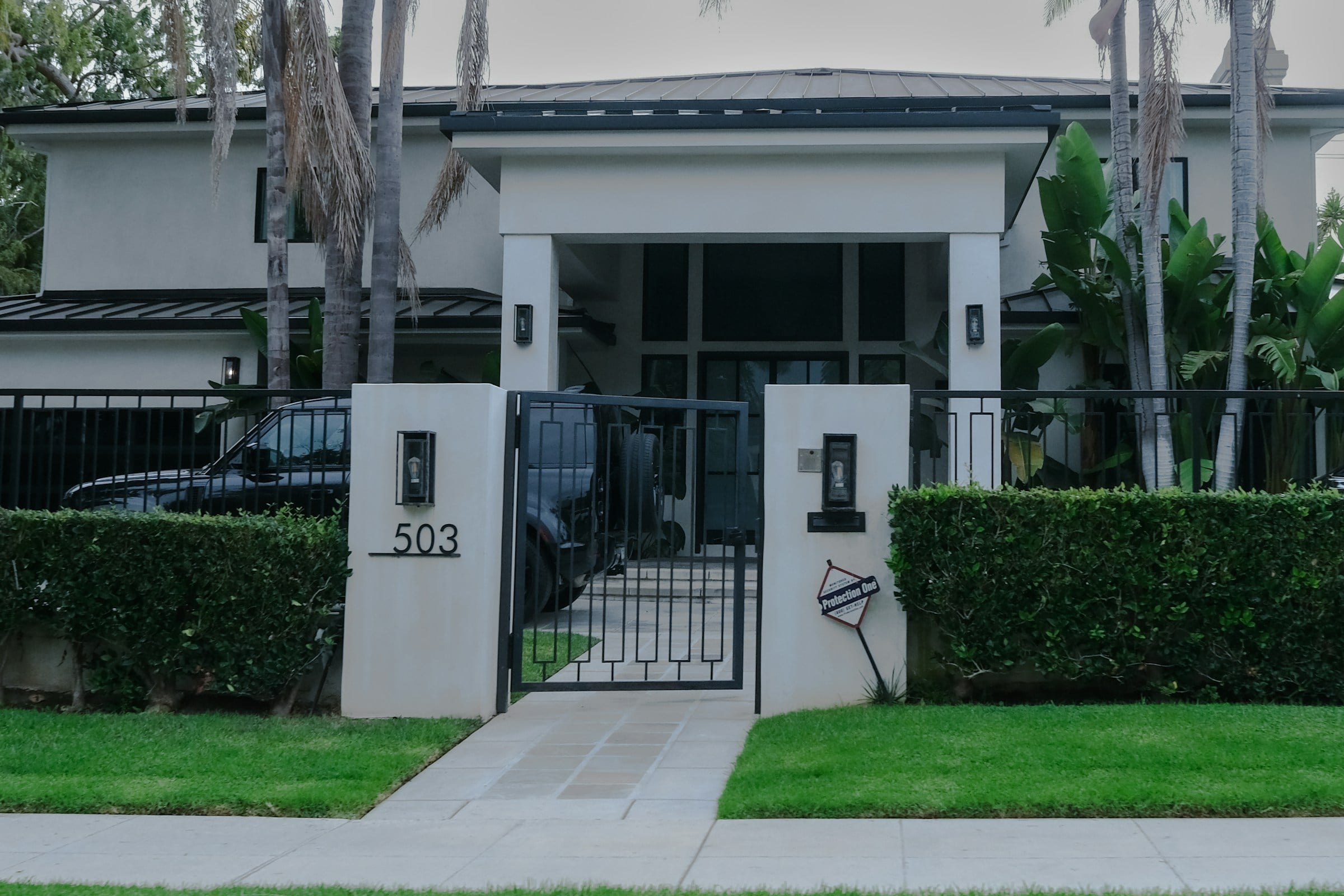 White house numbered 503 with a gate and mature trees